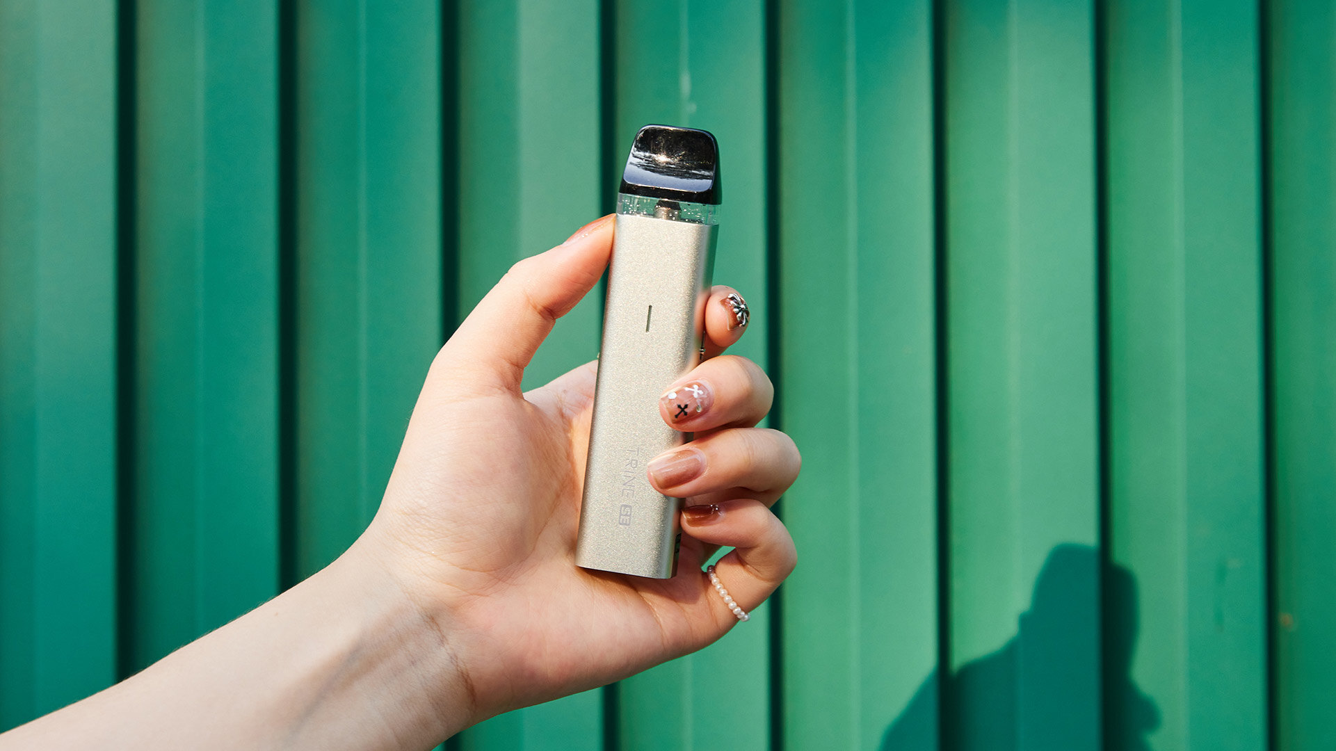 Hand holding an electronic cigarette device, illustrating the comparison of nicotine content between vaping and cigarettes.